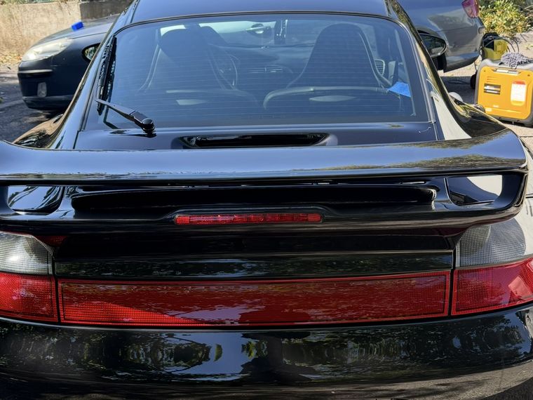 Porsche 911 noire après lavage et finition : carrosserie brillante, feux et aileron impeccables